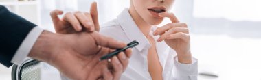 panoramic shot of businesswoman touching hand of businessman in office 