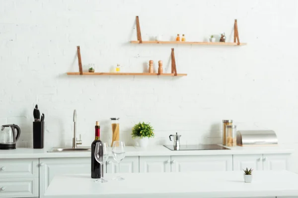 Botol Dengan Anggur Merah Dekat Gelas Kosong Atas Meja Dapur — Stok Foto