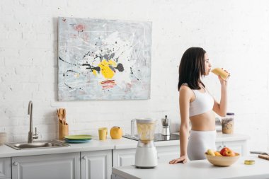 Mutfakta smoothie içen ince, güzel bir sporcunun yan görüntüsü