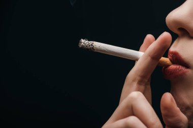 Side view of woman smoking cigarette isolated on black 