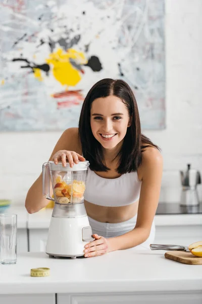 Selective Focus Attractive Sportswoman Smiling Camera While Preparing Smoothie Ripe — 图库照片