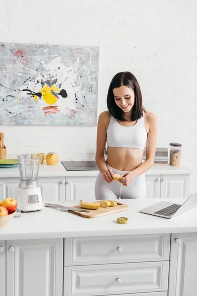 Smiling Sportswoman Preparing Smoothie Laptop Measuring Tape Kitchen Table — 스톡 사진