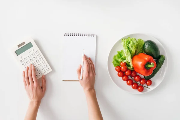 Visão Superior Mulher Usando Calculadora Perto Notebook Legumes Frescos Placa — Fotografia de Stock