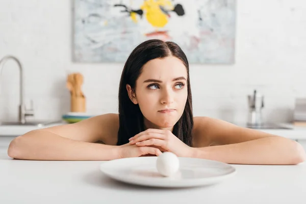 Pensive Fille Regardant Loin Près Oeuf Sur Plaque Sur Table — Photo