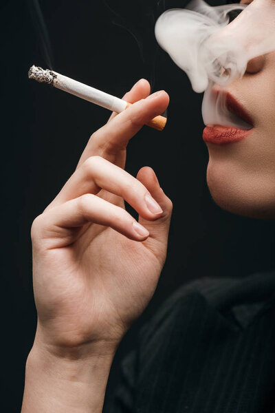 Обрезанный вид женщины, курящей сигарету изолированный на черном
 