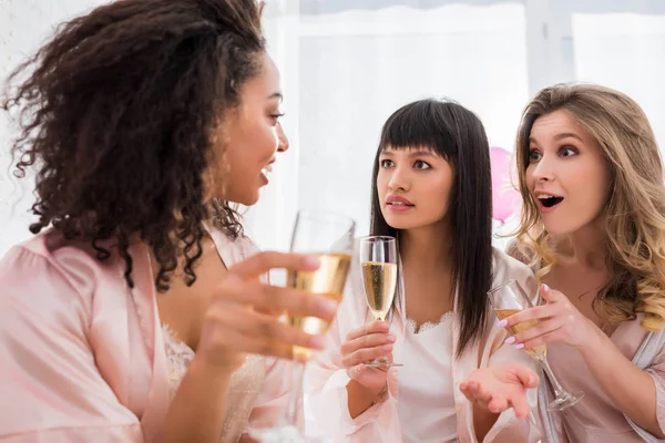 Sorprese Fidanzate Multietniche Con Bicchieri Champagne Parlando Sul Pigiama Party — Foto Stock