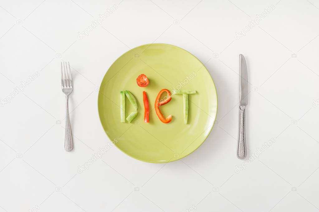 Top view of diet lettering on plate with cutlery on white background