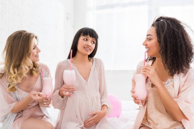 Çok kültürlü sevgililer ve bebek partisinde elinde milkshake olan hamile bir kadın. 