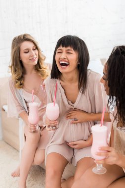Neşeli çok kültürlü sevgililer ve bebek partisinde elinde milkshake olan hamile bir kadın. 