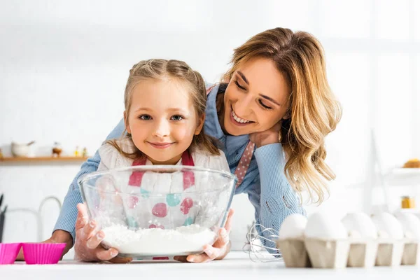 幸せなお母さんとかわいい娘の選択的な焦点は キッチンで小麦粉とボウルを保持 — ストック写真