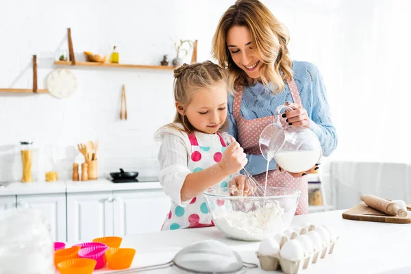 Selective Focus Daughter Kneading Dough While Mother Pouring Milk Jug — 스톡 사진