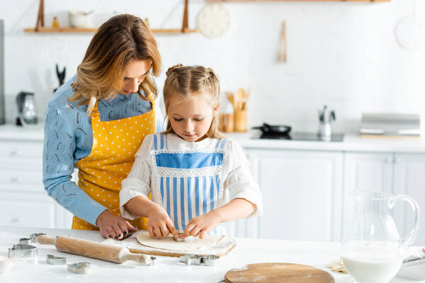 mother and daughter cooking with dough mold in kitchen 
