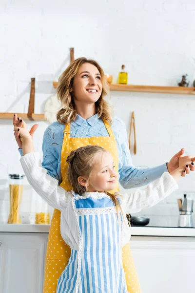 Sonriente Madre Cogida Mano Con Hija Mirando Cámara Cocina — Foto de Stock