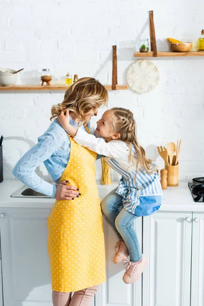 Πλαϊνή Όψη Χαμογελαστή Κόρη Αγκαλιάζει Μητέρα Στην Κουζίνα — Φωτογραφία Αρχείου