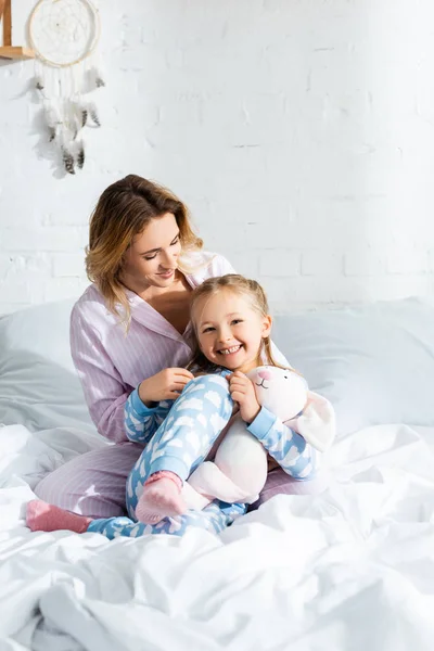 Gülümseyen Anne Pijamalı Tatlı Kız Yatakta Oturuyor — Stok fotoğraf