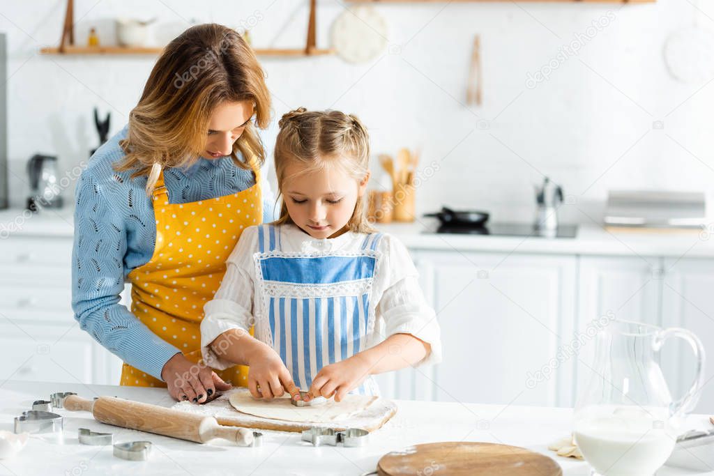 mother and daughter cooking with dough mold in kitchen 