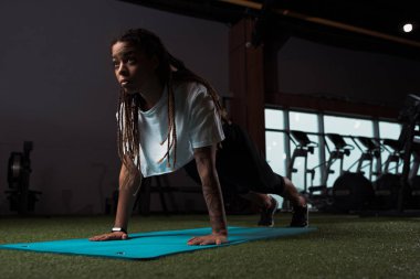 Afrika kökenli Amerikalı bir kadın spor paspasının üzerinde duruyor.