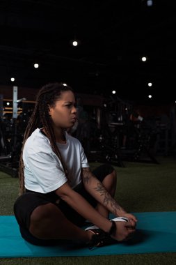 Endişeli ve hoşnutsuz Afro-Amerikan kadın bacak bacak üstüne atmış bir şekilde