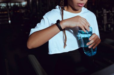 Cropped view of african american woman holding sports bottle of water clipart