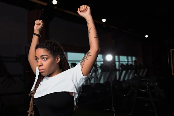 African american woman raising hands up in sports center