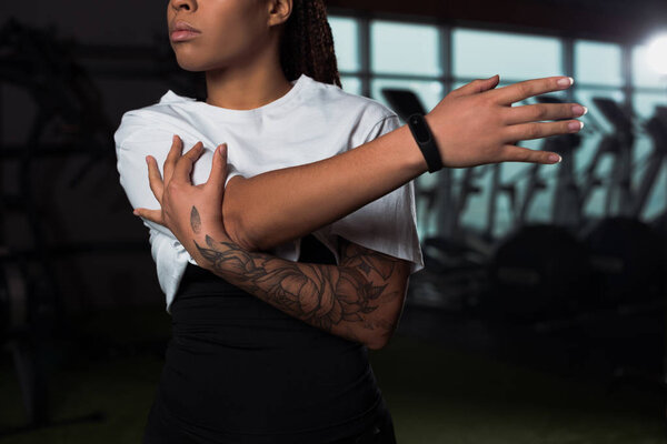Cropped view of african american woman stretching in gym