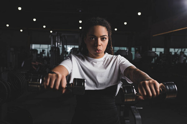 Selective focus of african american woman holding dumbbells