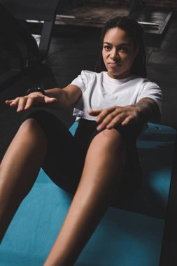 Afrika kökenli Amerikalı sporcu kadın Rasta ile spor paspası üzerinde egzersiz yapıyor.