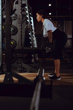 Halterle egzersiz yapan Afro-Amerikan sporcunun yan görünüşü 