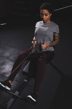 athletic african american girl with tattoo exercising in gym 