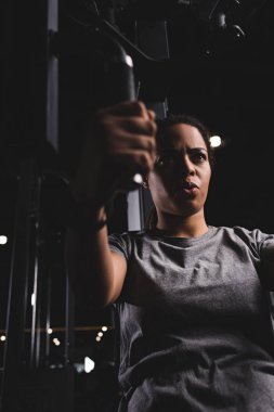 selective focus of young african american girl training on gym machine 