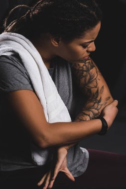 injured african american girl with tattoo touching hand in gym 
