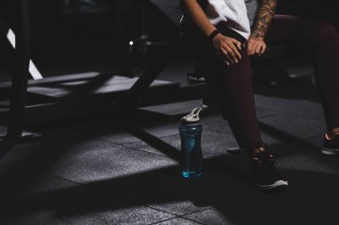 cropped view of tattooed african american woman touching knee in gym 