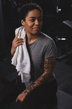 happy african american girl holding towel and smiling in gym 