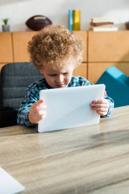 akıllı ve kıvırcık çocuk evde dijital tablet kullanıyor.