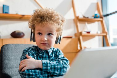 Laptop 'ın yanındaki kablosuz kulaklıkla müzik dinleyen çocuğun seçici odağı 