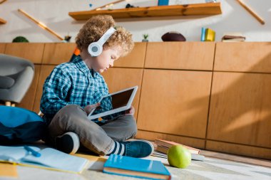 Kulaklıklı sevimli çocuğun boş ekranlı dijital tablet kullandığı seçici odak noktası 