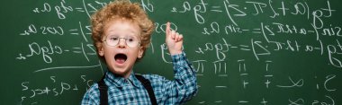 panoramic shot of kid in glasses having idea near chalkboard  clipart