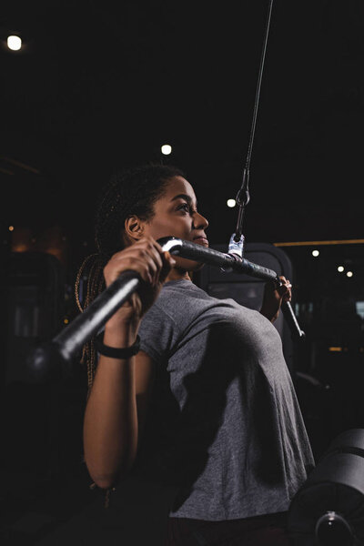 боковой вид молодой африканской девушки, тренирующейся в тренажерном зале
 