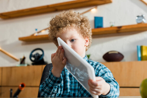 избирательный фокус умного и кудрявого ребенка с цифровым планшетом
 