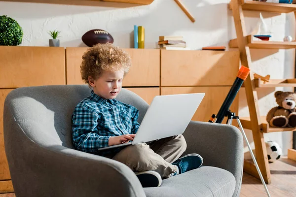 Χαριτωμένο Παιδί Κάθεται Στην Πολυθρόνα Και Χρήση Φορητού Υπολογιστή — Φωτογραφία Αρχείου