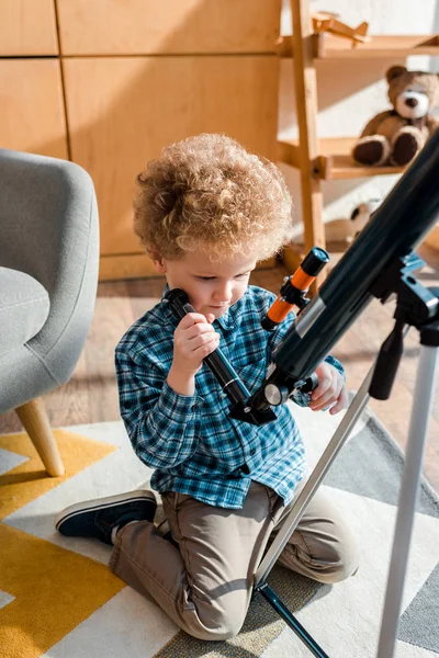 Niño Inteligente Tocar Telescopio Mientras Está Sentado Alfombra — Foto de Stock