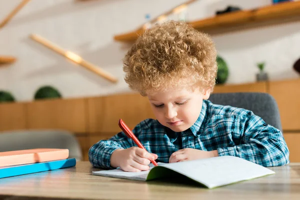 Niño Inteligente Escribiendo Cuaderno Cerca Libros Mesa —  Fotos de Stock