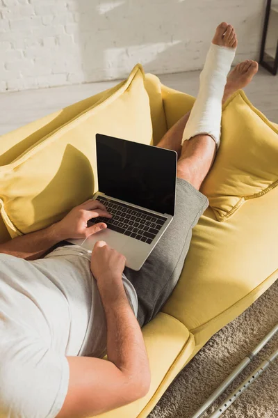 Cropped View Man Broken Leg Typing Laptop Sofa — Stock Photo, Image