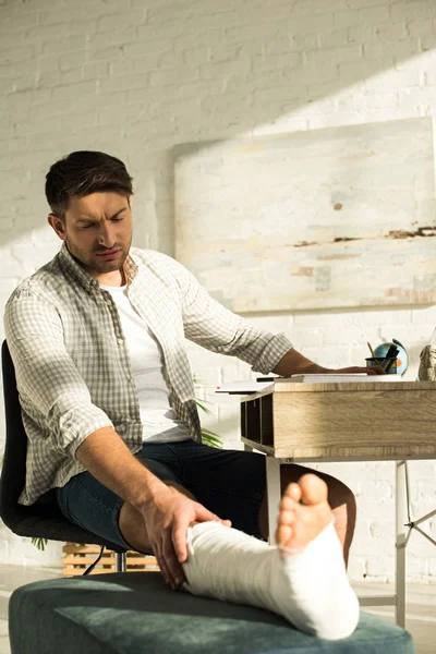 Selective Focus Handsome Man Touching Broken Leg While Sitting Table — 스톡 사진