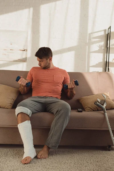 Hombre Guapo Con Pierna Rota Entrenando Con Mancuernas Sofá Casa — Foto de Stock