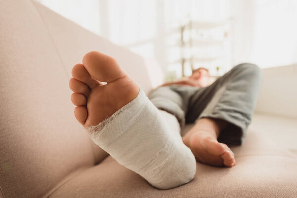 Selective focus of man with broken leg lying on couch