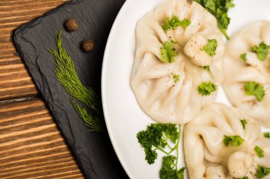 close up view of delicious Khinkali with cilantro on plate on brown wooden table