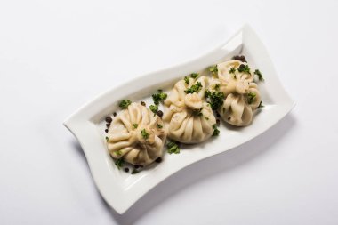 top view of delicious Khinkali with cilantro on plate on white background