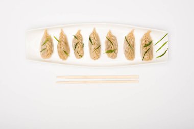 top view of delicious Chinese boiled dumplings on plate near chopsticks on white background