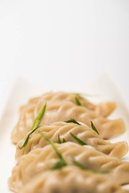 close up view of delicious Chinese boiled dumplings on plate near chopsticks on white background